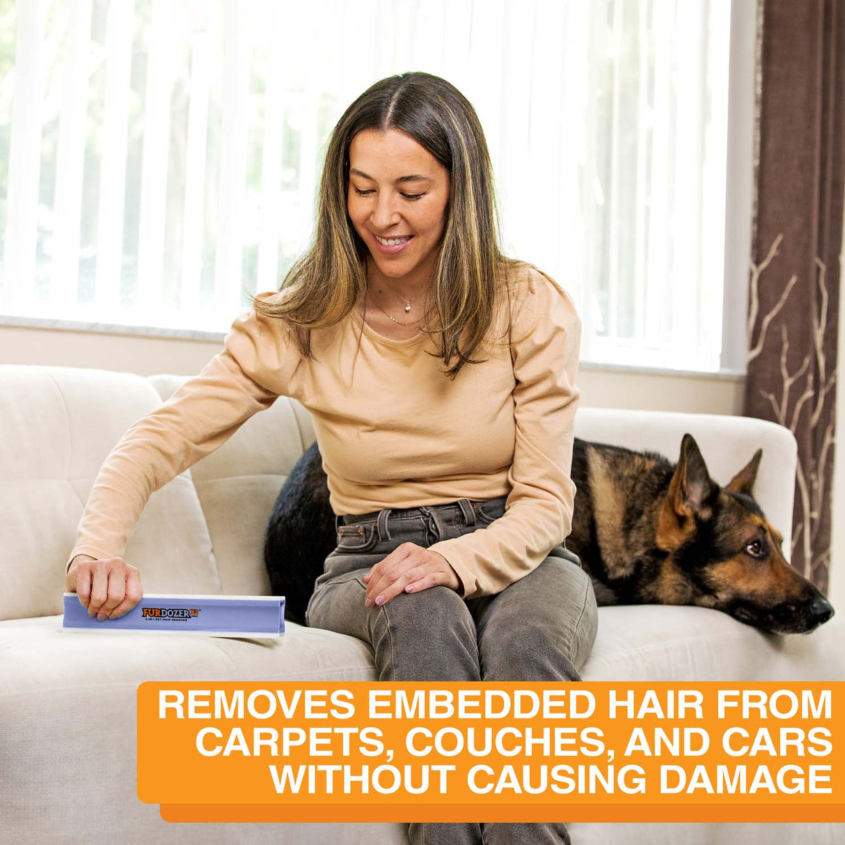 Woman using the Mega on the couch with a dog in the background. Text on screen reads: removes embedded hair from carpets, couches, and cars without causing damage.