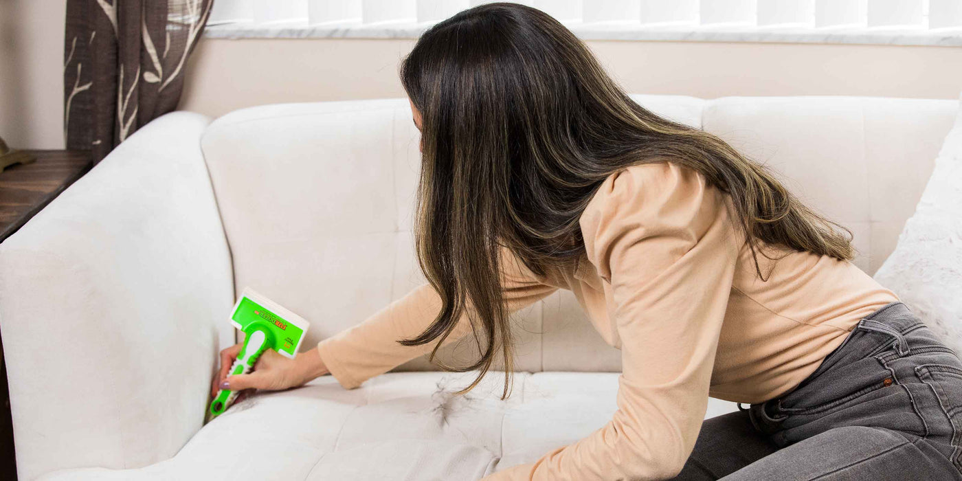 Woman using the crevice tool on the FurDozer X6 to clean in between couch cushions