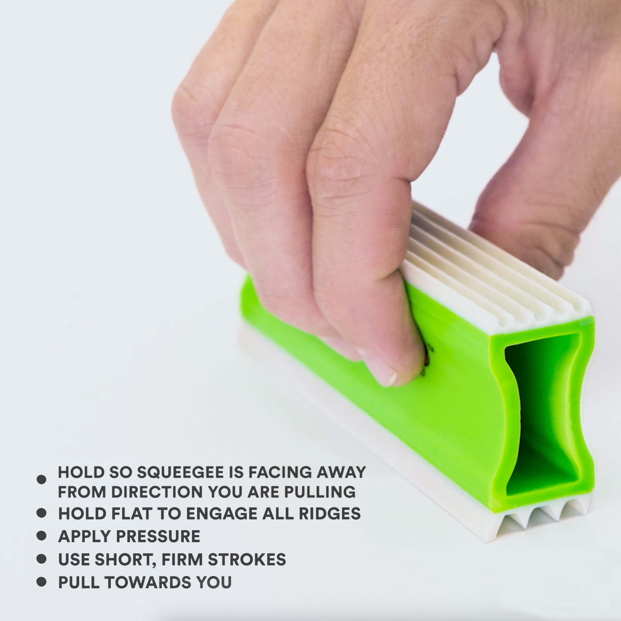 Close up of person holding the FurDozer correctly. Tips on screen read: Hold so squeegee is facing away from the direction you are pulling, hold flat to engage all ridges, apply pressure, use short, firm strokes, and pull towards you.