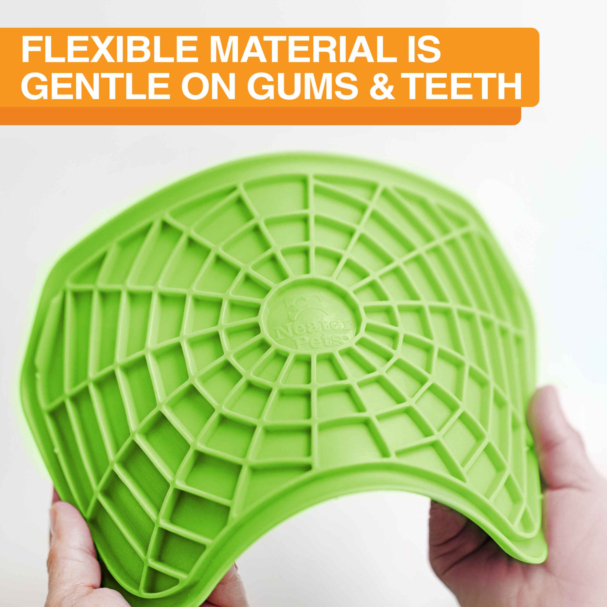 The Neat-Lik mat being spread apart to show the flexibility of the mat with the text "flexible material is gentle on gums and teeth."