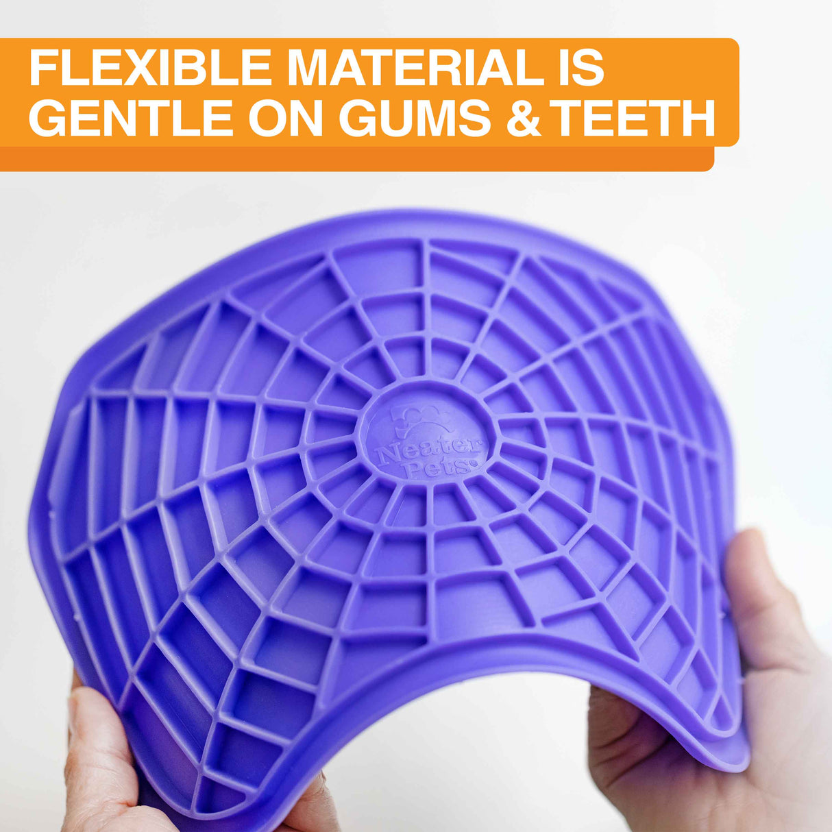 The Neat-Lik mat being spread apart to show the flexibility of the mat with the text "flexible material is gentle on gums and teeth."