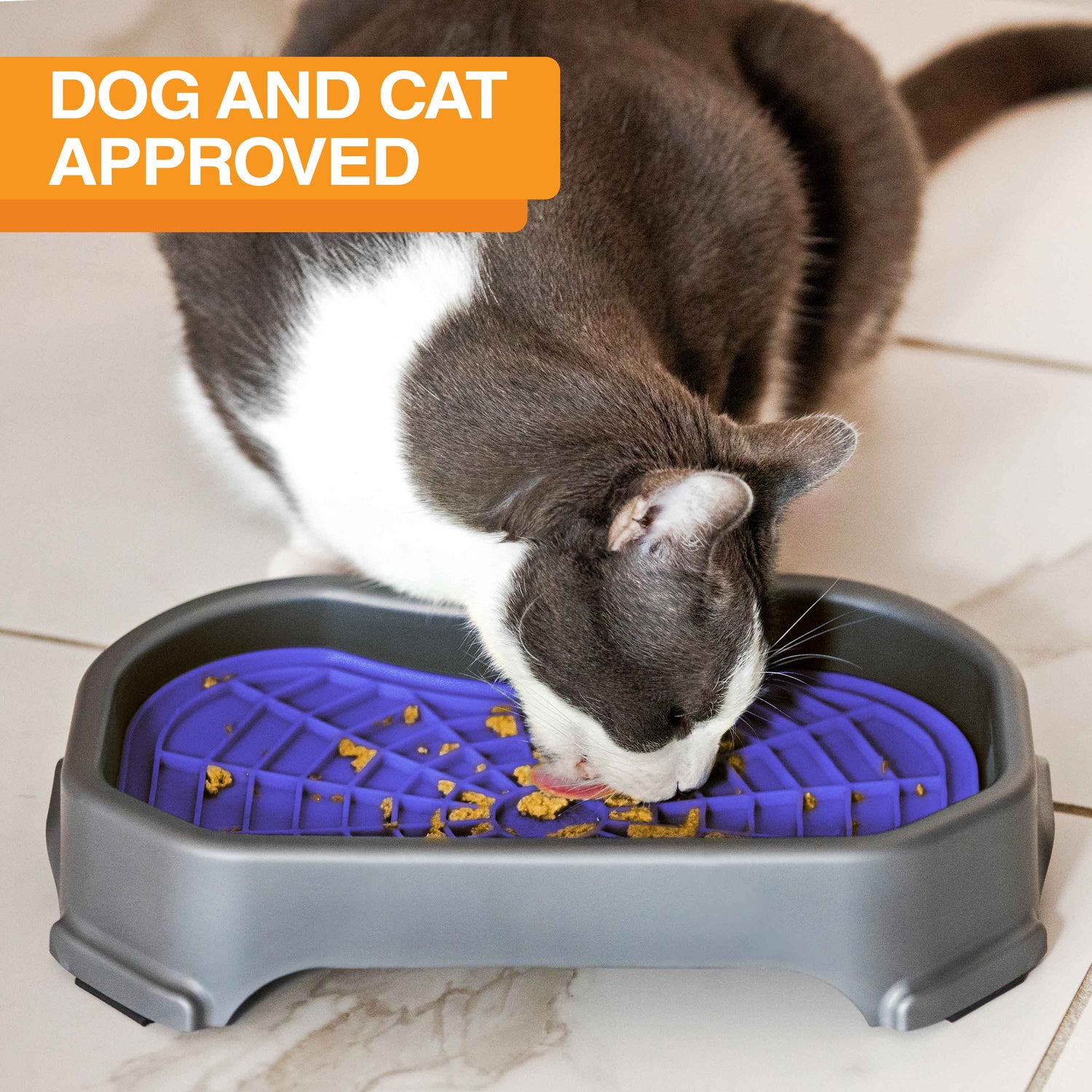Cat licking food out of the Neat-Lik Mat Slow Feed Licking Mat with the base with text that says "Dog and cat approved."