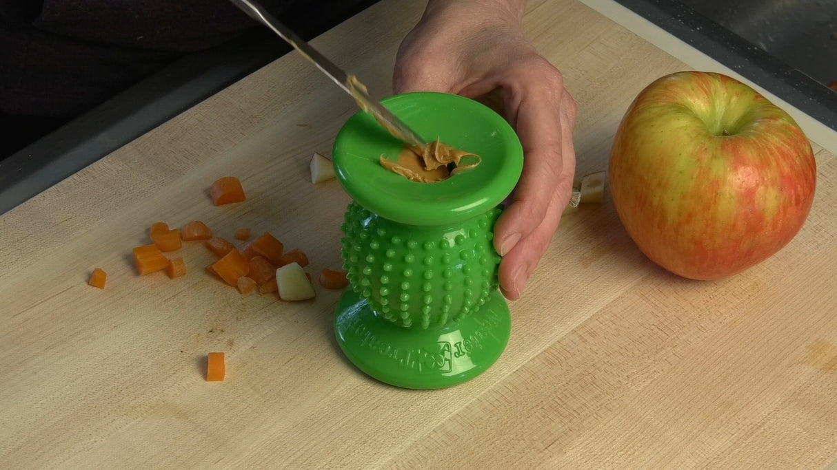 Bumpy Solid Green Rolly Cannoli with person placing peanut butter inside of it.