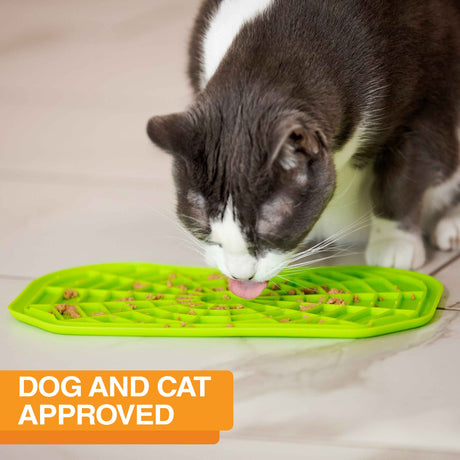 Cat licking food out of the Neat-Lik Mat Slow Feed Licking Mat directly on the ground