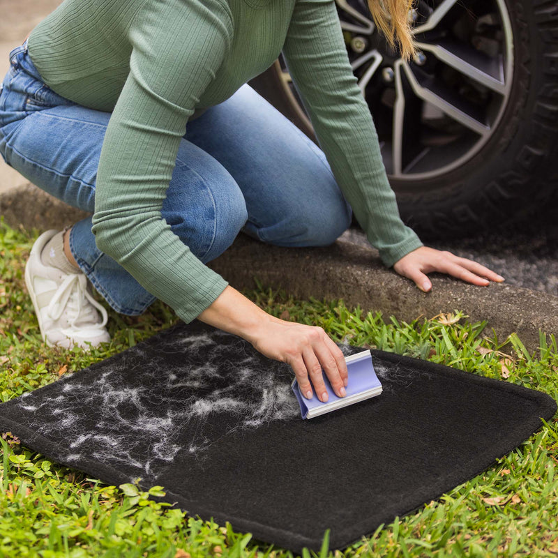 A woman is using the FurDozer X4 to clean a car mat covered in pet hair