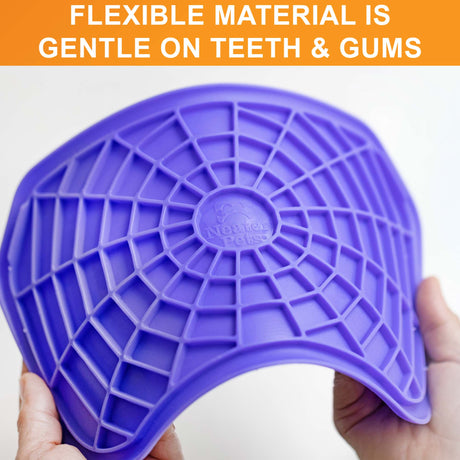 The Neat-Lik mat being spread apart to show the flexibility of the mat with the text "flexible material is gentle on gums and teeth."