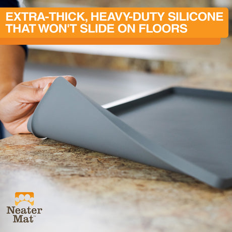 Gray Neater Mat being rolled out on a countertop with text above that says how the silicone bottom won't slide on floors.
